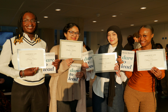 Young people smiling while holding graduation certificates